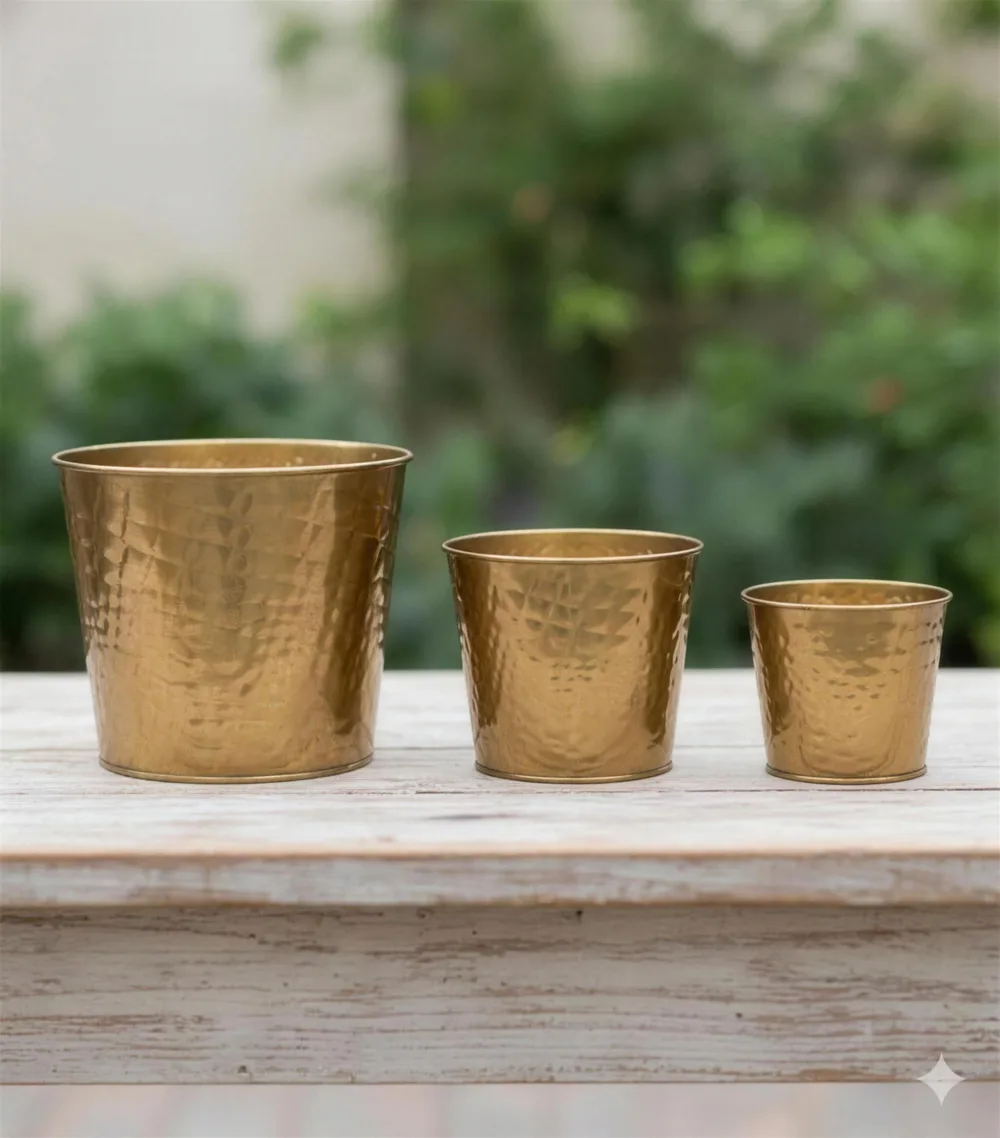 Trio de cachepôs martelados em dourado sobre uma bancada de madeira